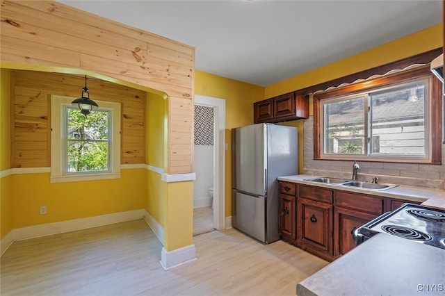 kitchen featuring freestanding refrigerator, a sink, light wood-style floors, and light countertops