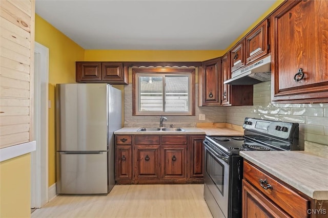 kitchen featuring appliances with stainless steel finishes, under cabinet range hood, a sink, and tasteful backsplash