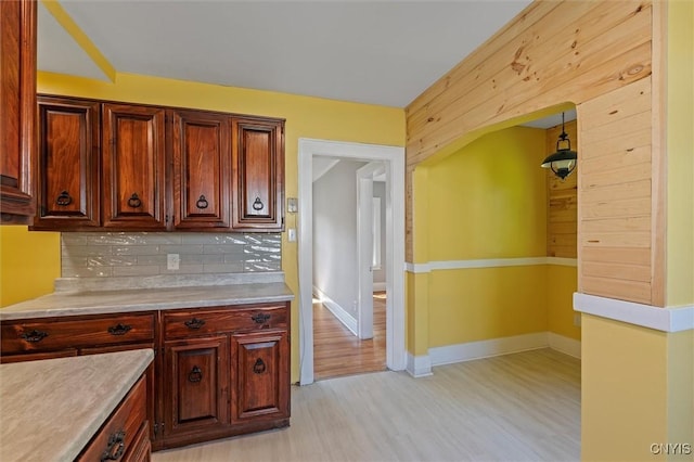 kitchen featuring decorative backsplash, light countertops, light wood finished floors, and baseboards