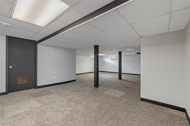 basement featuring baseboards, a paneled ceiling, and carpet flooring