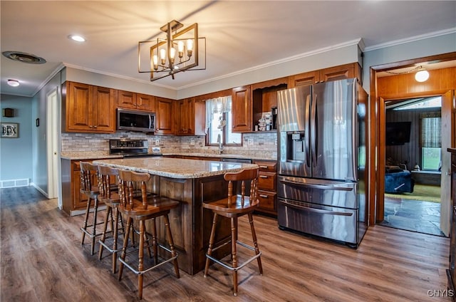 7732 Gifford Rd, Rome-Inside, NY 13440 - kitchen featuring stainless steel appliances, crown molding, tasteful backsplash, brown cabinets, and a breakfast bar area