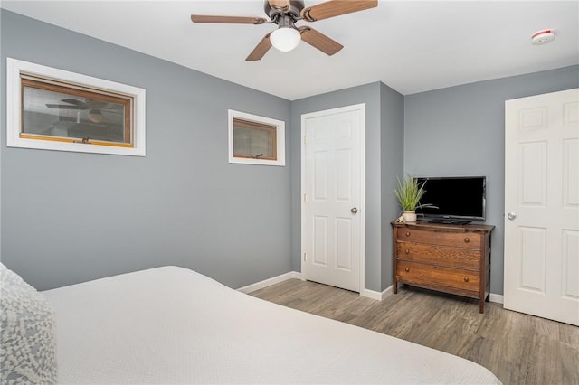 bedroom featuring wood finished floors, baseboards, and ceiling fan