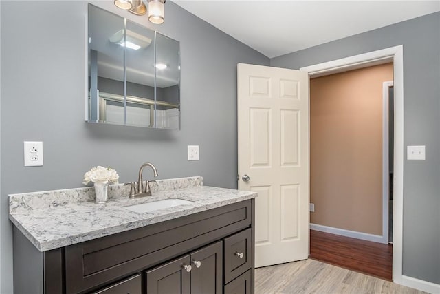 bathroom with wood finished floors, baseboards, and vanity