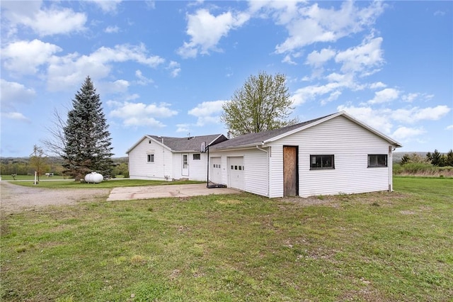 back of property with concrete driveway, a yard, and a garage