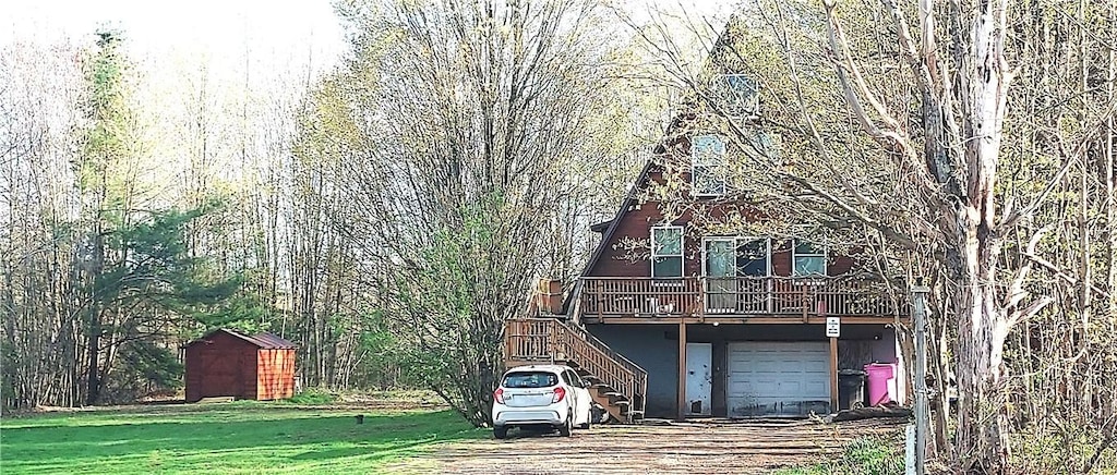 view of front facade with stairway, a storage shed, driveway, a deck, and a front lawn