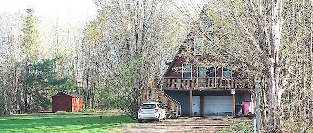 view of front facade with stairway, a storage shed, driveway, a deck, and a front lawn