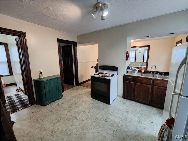 kitchen featuring electric range, a sink, freestanding refrigerator, light marble finish floors, and a textured ceiling