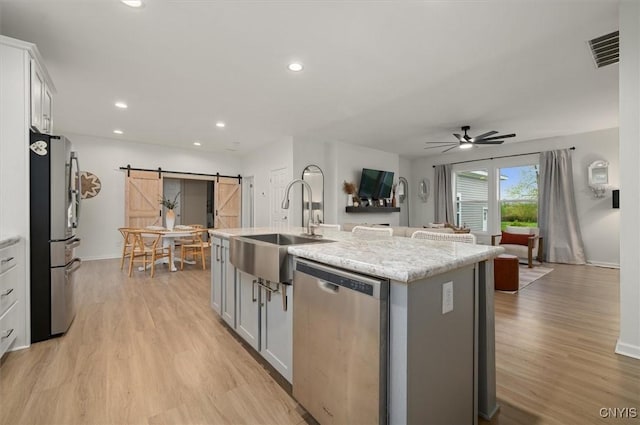 161 Knapps Knolle Rd, Schuyler, NY 13502 - kitchen featuring stainless steel appliances, a sink, a barn door, ceiling fan, and light wood-style flooring