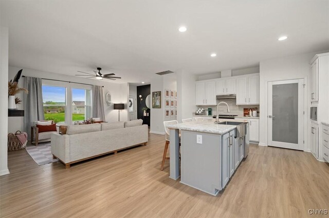 161 Knapps Knolle Rd, Schuyler, NY 13502 - kitchen with light wood finished floors, white cabinetry, a ceiling fan, open floor plan, and under cabinet range hood