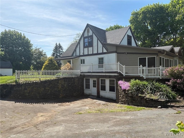 back of house featuring a deck, fence, and a shingled roof