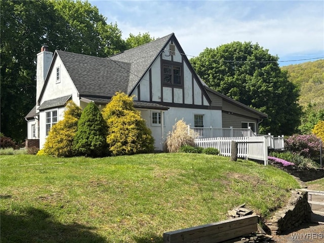 rear view of property with stucco siding, a yard, roof with shingles, and a chimney
