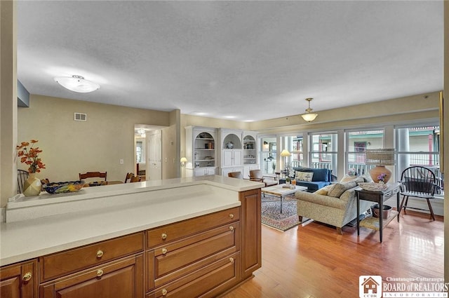 14 S Lake Dr Unit 2B, Chautauqua, NY 14722 - kitchen featuring open floor plan, brown cabinets, light countertops, a peninsula, and light wood-type flooring