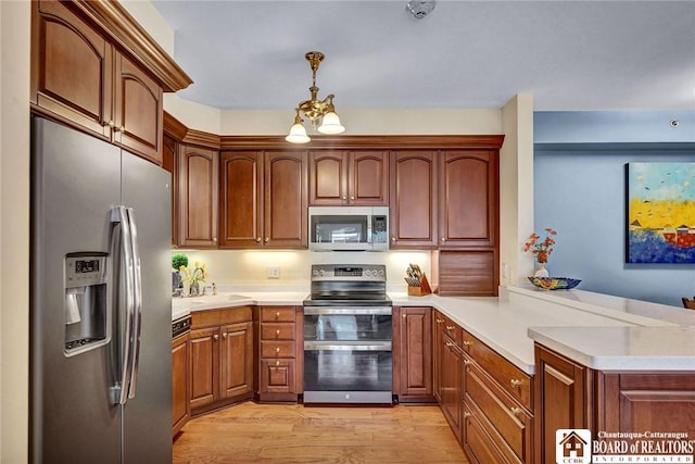 14 S Lake Dr Unit 2B, Chautauqua, NY 14722 - kitchen featuring stainless steel appliances, a peninsula, light countertops, light wood-type flooring, and hanging light fixtures