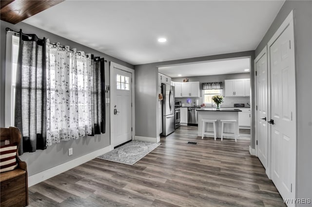 foyer with recessed lighting, healthy amount of natural light, dark wood-type flooring, and baseboards
