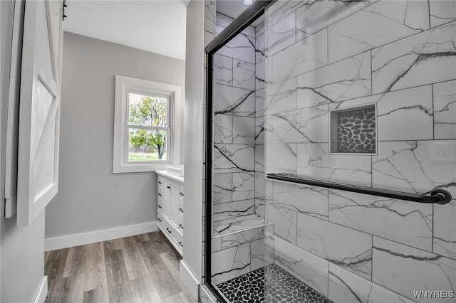 full bathroom with a marble finish shower, vanity, wood finished floors, and baseboards