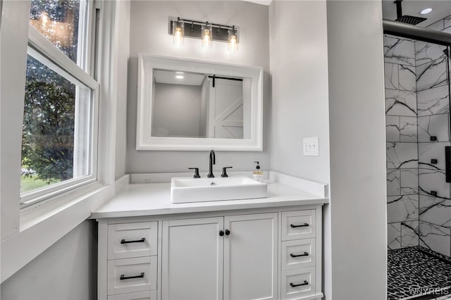 bathroom with a marble finish shower, healthy amount of natural light, and vanity