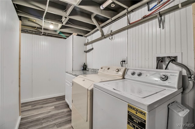 laundry room with washing machine and clothes dryer, light wood-type flooring, cabinet space, and baseboards