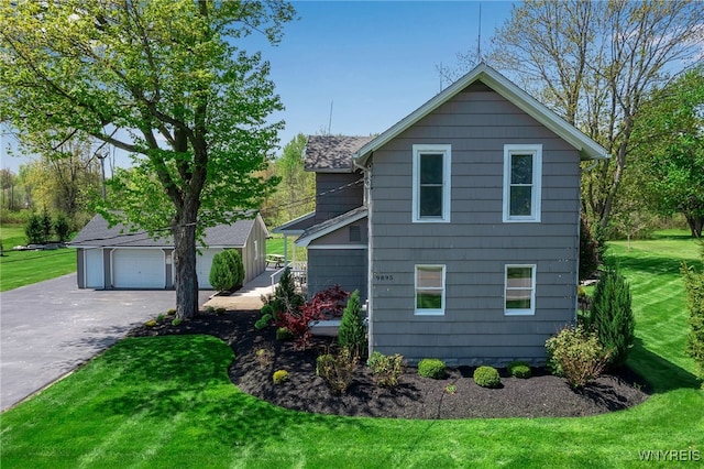 view of front of home featuring an outdoor structure, a front lawn, and a detached garage