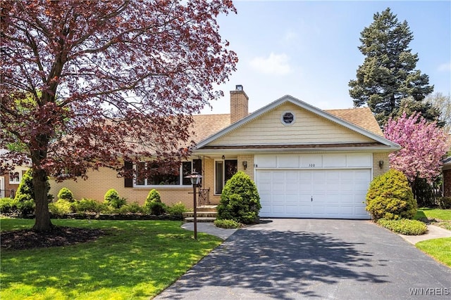 view of front of property with driveway, a front lawn, a chimney, an attached garage, and brick siding