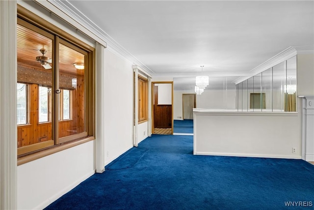 empty room with dark carpet, a chandelier, ornamental molding, and baseboards