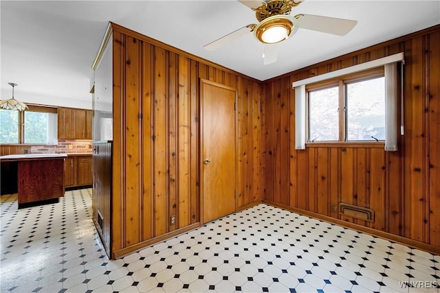 empty room with light floors, ceiling fan, and wooden walls
