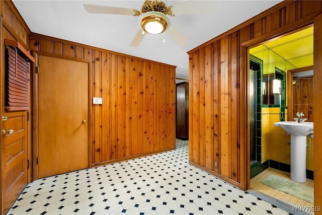unfurnished room with a ceiling fan and wooden walls
