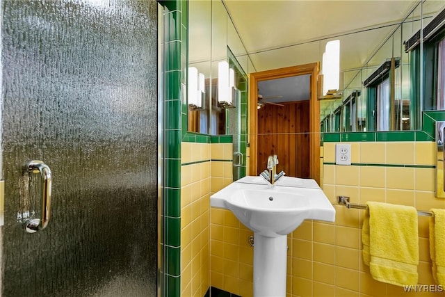 bathroom with tile walls, a stall shower, and a ceiling fan
