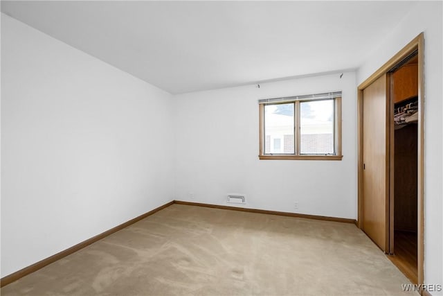 unfurnished bedroom with light carpet, baseboards, and a closet