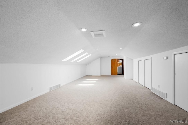 additional living space with carpet floors, vaulted ceiling, a textured ceiling, recessed lighting, and a skylight
