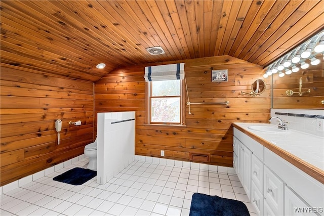 bathroom featuring lofted ceiling, toilet, tile patterned floors, vanity, and wood walls