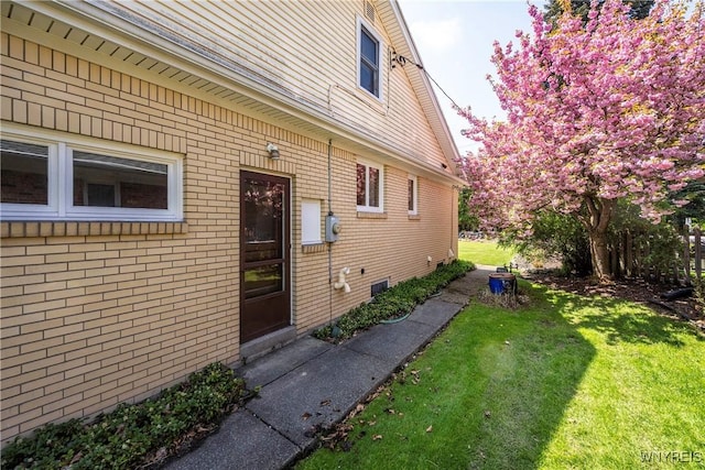 view of side of property featuring brick siding and a lawn