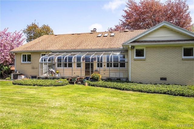 back of property featuring brick siding, a lawn, a chimney, central AC, and a sunroom