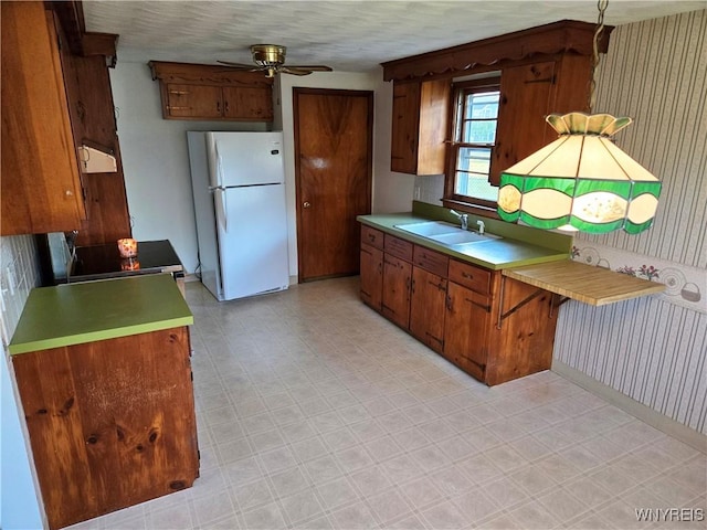 585 Downing St, Buffalo, NY 14220 - kitchen featuring freestanding refrigerator, ceiling fan, light countertops, wallpapered walls, and brown cabinetry
