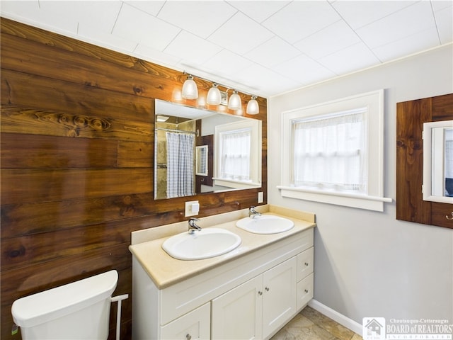 full bath with toilet, double vanity, baseboards, and a shower with curtain