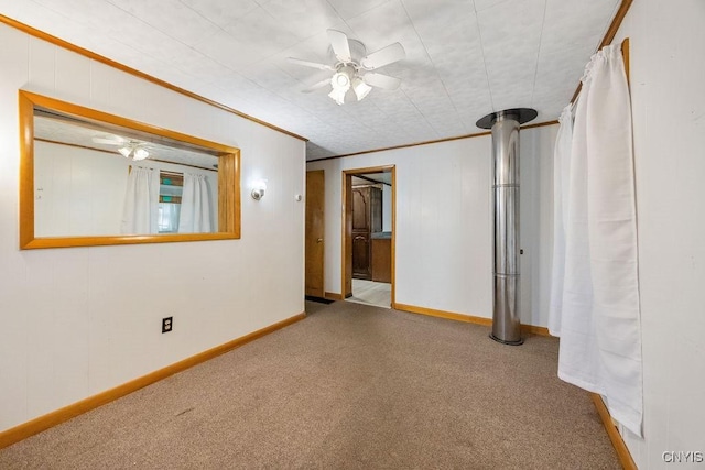 carpeted empty room with a ceiling fan, ornamental molding, and baseboards