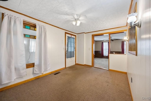 carpeted spare room with a ceiling fan, ornamental molding, and baseboards