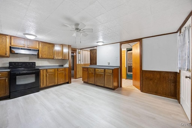 kitchen featuring black range with electric stovetop, under cabinet range hood, dark countertops, brown cabinetry, and light wood finished floors