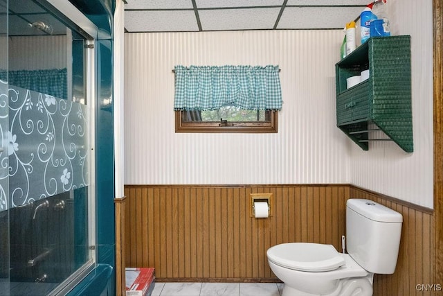 full bath featuring a shower stall, toilet, and a wainscoted wall