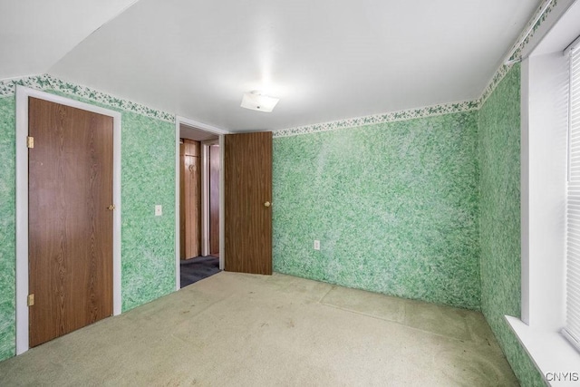 carpeted empty room with wallpapered walls