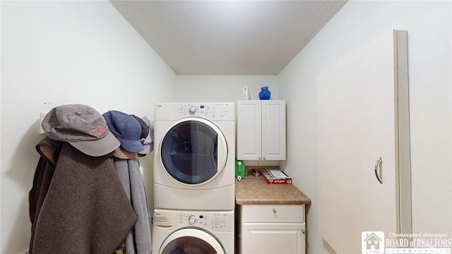clothes washing area with stacked washer and clothes dryer and cabinet space