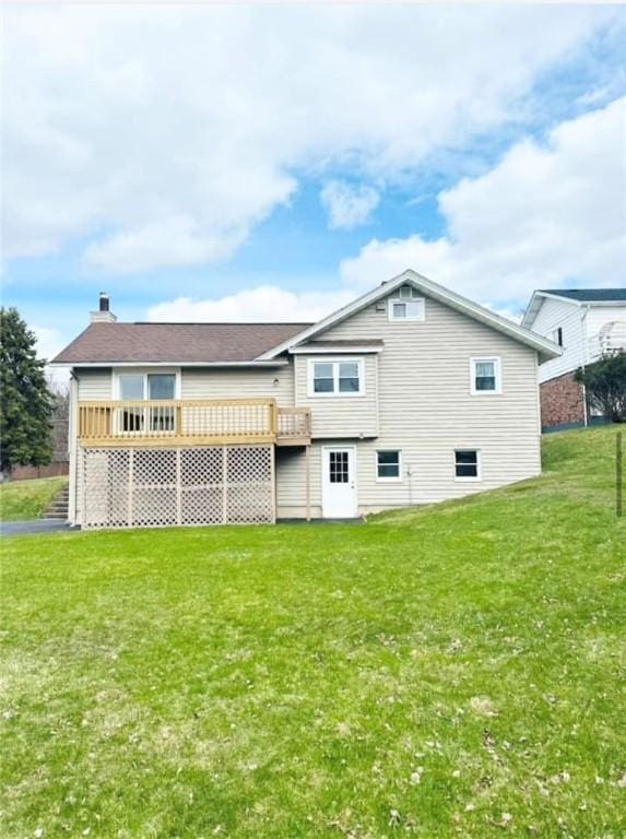 back of property featuring a deck and a lawn