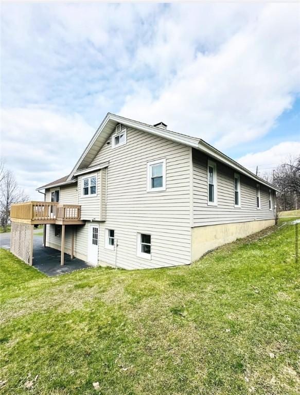 view of home's exterior featuring a wooden deck and a lawn
