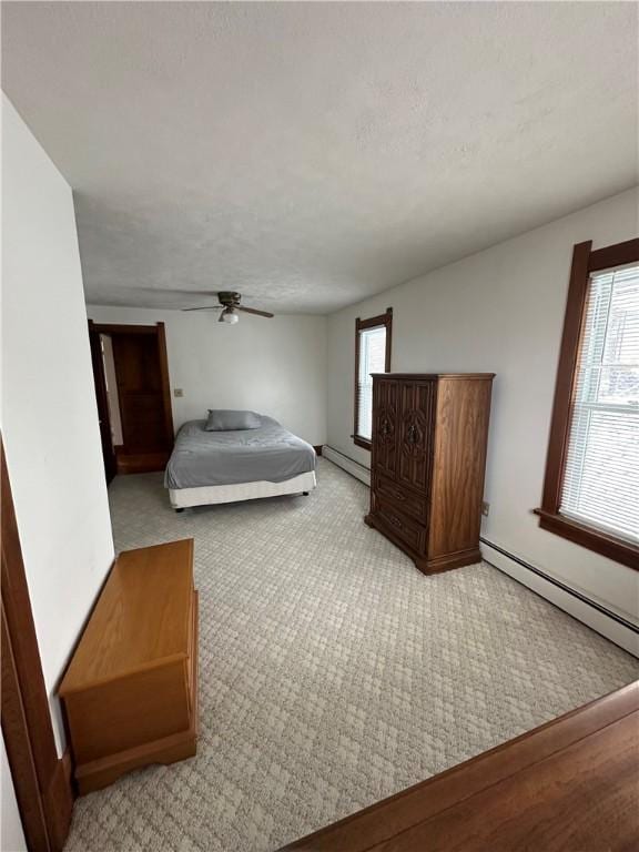 bedroom with baseboard heating, light carpet, ceiling fan, and a textured ceiling