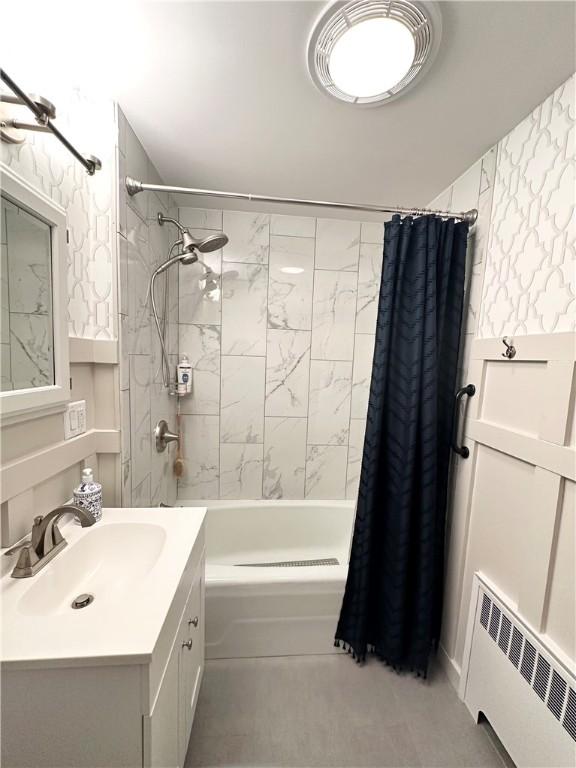 full bathroom featuring radiator heating unit, shower / bath combination with curtain, and vanity