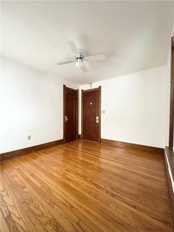 empty room featuring baseboards, wood finished floors, and a ceiling fan