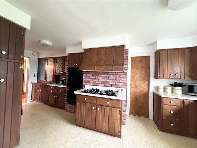 kitchen featuring black appliances, light countertops, custom range hood, a sink, and light floors