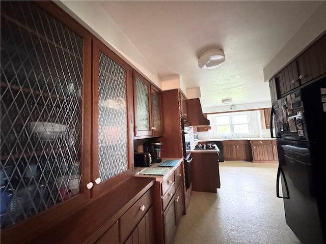 kitchen featuring freestanding refrigerator, light countertops, and a sink
