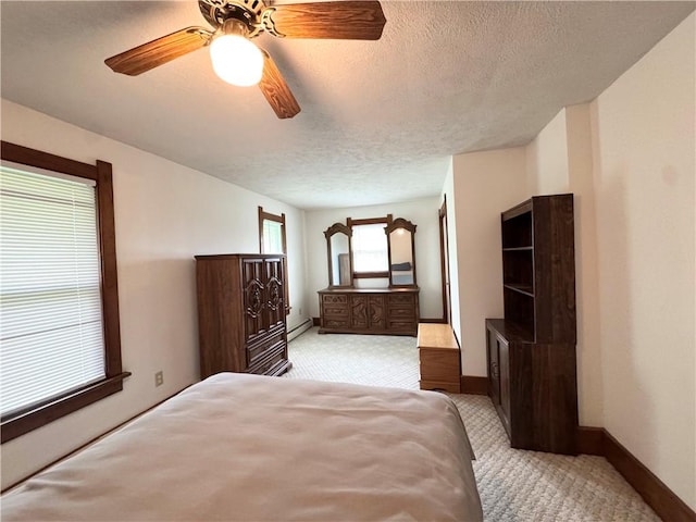 bedroom with light carpet, a textured ceiling, baseboards, a ceiling fan, and baseboard heating