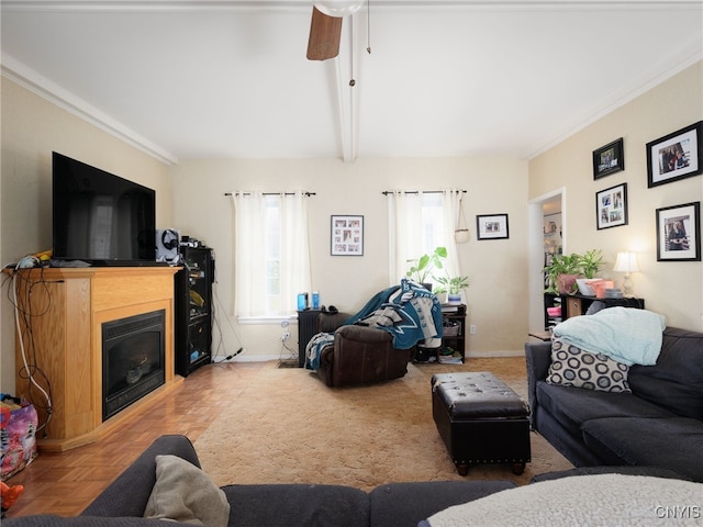 living room with a ceiling fan, baseboards, crown molding, a glass covered fireplace, and beamed ceiling