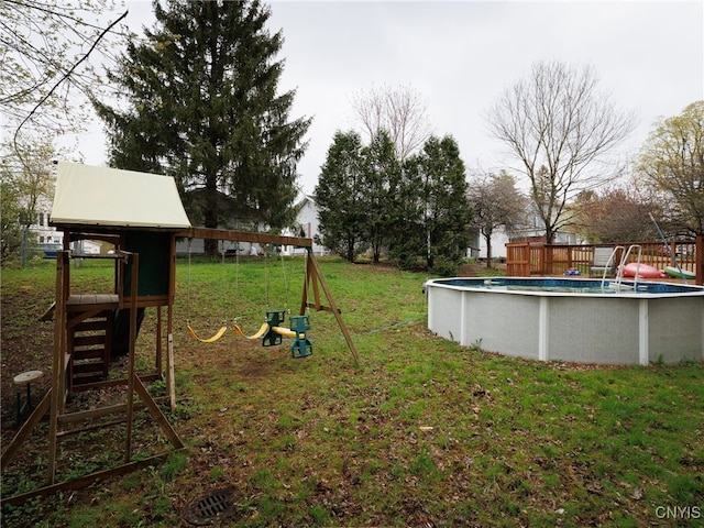 view of grassy yard featuring a playground and an outdoor pool
